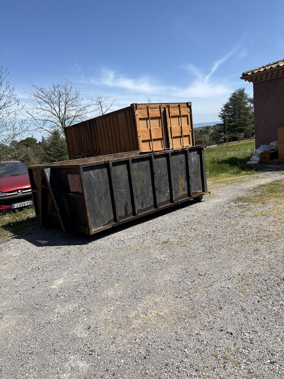 Benne de location déposée devant une maison